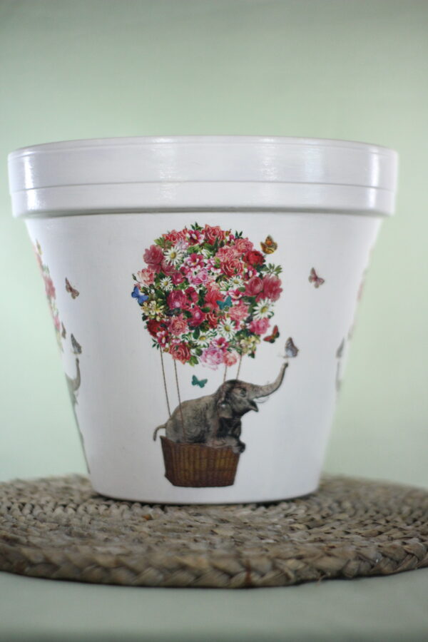 Elephant pot in a hot air balloon covered in flowers with a green background