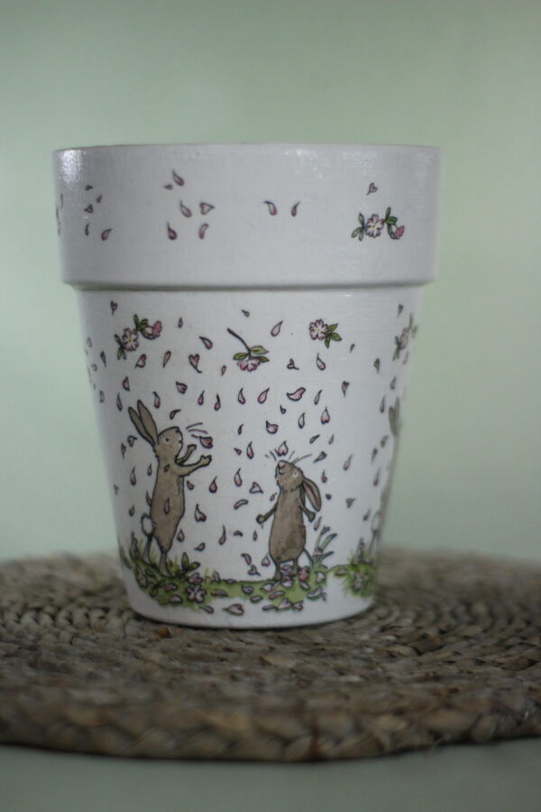 Plant pot with rabbit design on it, dancing in petals