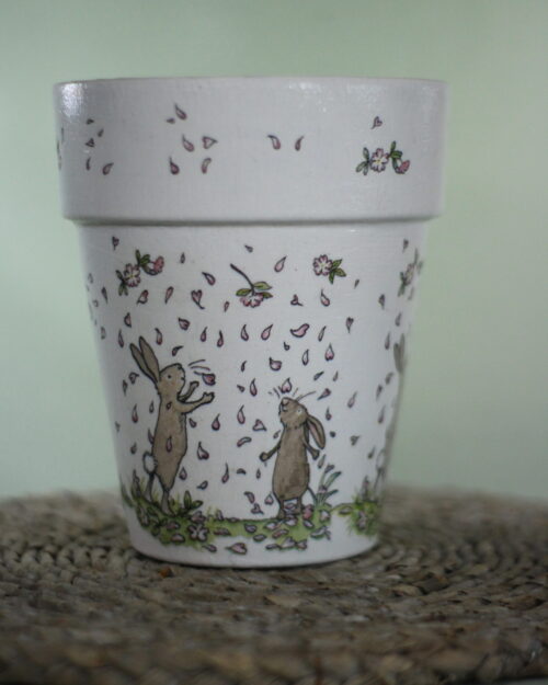 Plant pot with rabbit design on it, dancing in petals