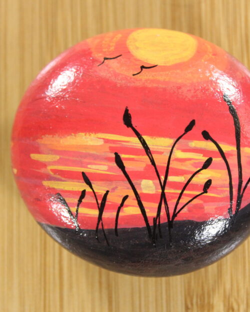 red sunset with reeds painted pebble